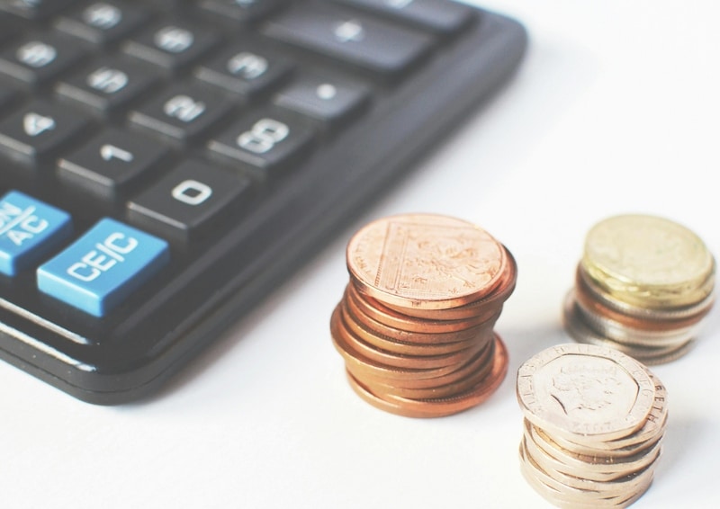 Calculadora junto a monedas apiladas representando el control de gastos, ahorro y planificación de metas financieras personales