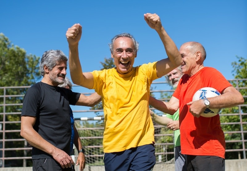 Un grupo de hombres celebra alegremente mientras sostienen un balón de fútbol.